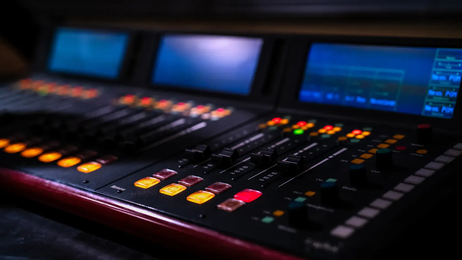 A broadcast mixing console with illuminated controls in a radio studio